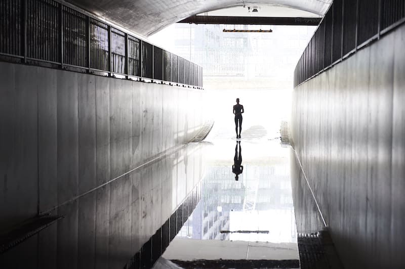 A figure (Kate) stands at the end of a long tunnel.